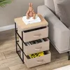 A bedside table with three fabric drawers is placed next to a sofa in a living room setting. Podgląd zdjęcia produktu