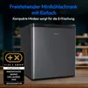 A gray mini-refrigerator is shown on a wooden surface with a blurred background of a room interior. There is a promotional award badge on the left and text overlays at the top. Produktbild-Vorschau