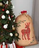 A Christmas sack with a reindeer design next to a decorated Christmas tree. Anteprima dell’immagine prodotto