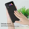 A person's hands are holding a black flip phone case, with text describing its texture. Náhled obrázku produktu