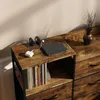 A close-up shot of a wooden dresser with drawers and shelves, featuring electronic devices charging on top. Náhľad obrázku produktu