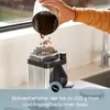 A person is pouring coffee beans into a coffee grinder. Produktbild-Vorschau