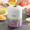 A finger presses the button on a portable mini chopper filled with chopped red onions. Other ingredients like avocado, tomatoes, and minced meat are visible in the background. Náhľad obrázku produktu