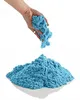 A hand holding blue kinetic sand over a pile of the same sand. Voir les images du produit