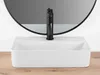 A white rectangular vessel sink with a black faucet in front of a round mirror. Podgląd zdjęcia produktu