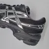 A close-up side view of a black and silver Asics running shoe. Produktbild-Vorschau