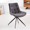 A gray upholstered dining chair with a black metal base is shown in a room with white wooden floors and a wooden cabinet in the background. Produktbild-Vorschau