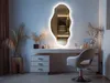 A modern vanity area with a large, irregularly shaped mirror with LED backlighting, a white vanity desk with drawers, and a white chair. Produktbild-Vorschau