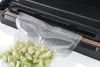 A vacuum sealer bag filled with chopped green vegetables is being placed into a vacuum sealer machine. Náhľad obrázku produktu
