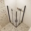 A corner shower enclosure with a black frame and frosted glass doors, set in a bathroom with tiled walls and terrazzo flooring. Produktbild-Vorschau