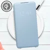 A light blue flip case for a smartphone is shown on a white wireless charging pad, with a Qi logo visible. Anteprima dell’immagine prodotto