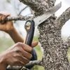A person is using a Fiskars folding saw to cut a tree branch. Produktbild-Vorschau