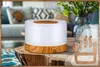 An aroma diffuser is placed on a wooden table in a living room setting. Produktbild-Vorschau