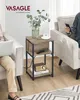A side table with a vintage radio and books on the lower shelf, a cup of coffee on the top shelf, and a vase with greenery. People are sitting on chairs on either side of the table, one using a laptop and the other a phone. Produktbild-Vorschau