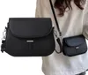 A person wearing a white sweater is shown with two black handbags, one larger and one smaller, in the foreground. Náhľad obrázku produktu