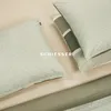 Close-up view of bedding, including pillows and a fitted sheet, in various shades of green and beige. Produktbild-Vorschau