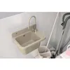 A beige sink with a faucet is mounted on a tiled wall, with cleaning supplies like a mop and bucket nearby. Anteprima dell’immagine prodotto