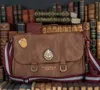 A brown leather messenger bag with Hogwarts crests and a striped strap, placed in front of a bookshelf filled with old books. Anteprima dell’immagine prodotto