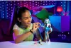 A young girl is playing with a doll in a bedroom decorated with string lights. Produktbild-Vorschau
