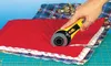 A hand is using a yellow rotary cutter to cut a stack of quilted fabric pieces on a green cutting mat. Produktbild-Vorschau