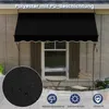 A black awning is installed above a window on a building, with a small table and chair set in front of it. A close-up inset shows the texture of the awning material with water droplets. Anteprima dell’immagine prodotto