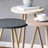 Three nesting side tables with round tops in different colors and wooden legs, set against a gray background. Produktbild-Vorschau