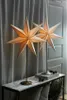 Two star-shaped lamps are displayed on a marble-top console table, with curtains in the background. Podgląd zdjęcia produktu