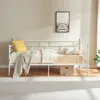A white metal daybed with bedding and a pillow, placed against a light-colored wall with a framed picture above it. Podgląd zdjęcia produktu