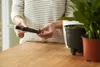 A person is holding a plant watering device next to potted plants. Produktbild-Vorschau