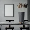A dark gray planter with dried reeds sits on a rustic wooden table in front of a gray wall with a framed picture. Anteprima dell’immagine prodotto