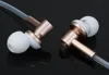 A close-up shot of two rose gold and white in-ear headphones against a black reflective background. Produktbild-Vorschau