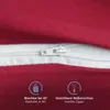 A close-up view of a red fabric with a white zipper, showing care instructions and feature highlights. Produktbild-Vorschau