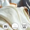 A close-up of a soft, cream-colored blanket draped over a chair. Produktbild-Vorschau