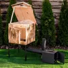 A wooden smoker oven with a black metal chimney and firebox, set up on a green lawn in a garden setting. Náhled obrázku produktu