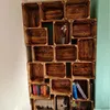 A wall-mounted bookshelf made of wooden crates, filled with books and a small plant. Náhled obrázku produktu