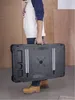 A person is carrying a folded black work bench. Náhľad obrázku produktu
