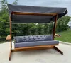 A wooden swing set with cushions and a canopy, placed on a patio outdoors. Podgląd zdjęcia produktu