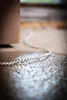 A close-up shot of a rope lying on a wet, textured surface, with a blurred brown object in the background. Podgląd zdjęcia produktu
