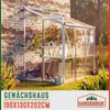 A greenhouse attached to a brick wall, with plants inside and grass in the foreground. Náhled obrázku produktu