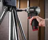 A person is using a cordless impact driver to attach a metal component to a tripod-like structure. Produktbild-Vorschau