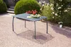 A garden table and chairs set on a brick patio, surrounded by lush greenery and blooming roses. Produktbild-Vorschau