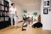 A woman vacuums her living room while her dog sleeps nearby. Podgląd zdjęcia produktu