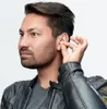 A man is inserting an earplug into his ear. Anteprima dell’immagine prodotto