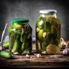Two jars of pickles with garlic and dill on a wooden table. Podgląd zdjęcia produktu