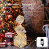 A decorated Christmas tree with gift boxes and illuminated gift box decorations in a cozy indoor setting. Produktbild-Vorschau