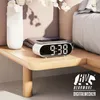 A digital alarm clock with wireless charging is placed on a wooden nightstand next to a bed. Anteprima dell’immagine prodotto