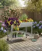 A raised garden bed filled with flowers and plants in a backyard setting. Produktbild-Vorschau