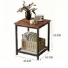 A square side table with a wood-look top and black metal frame, featuring a shelf with a woven basket filled with books. Produktbild-Vorschau