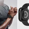 A split image showing a person wearing a black Apple Watch case on their left wrist and a close-up view of the back of a black Apple Watch case. Produktbild-Vorschau
