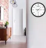 A hallway with a wooden cabinet, a brick wall, and a modern wall clock. Produktbild-Vorschau